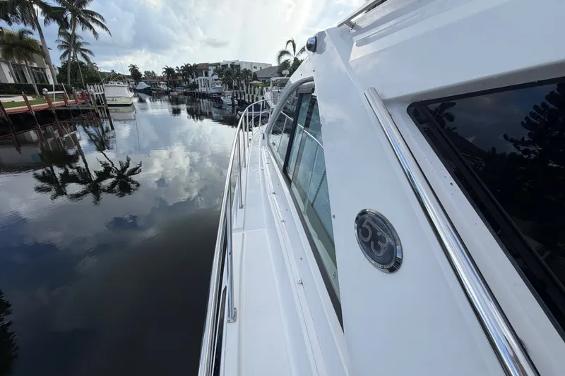 Slide: The Image of 2018 Regal 53 Sport Coupe yacht docked by a serene waterfront with palm trees. - 38