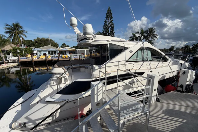 Slide: The Image of 2018 Regal 53 Sport Coupe yacht docked, surrounded by palm trees and waterfront homes. - 6