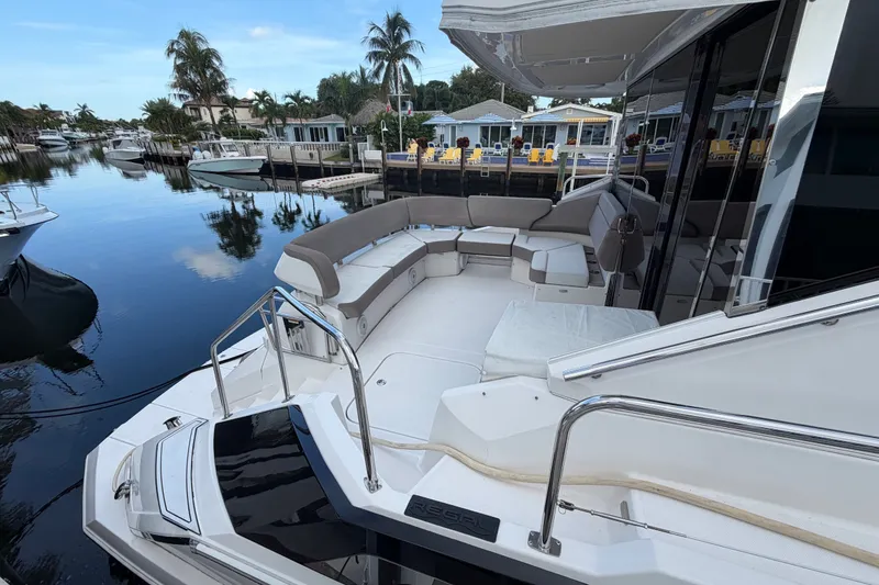 Slide: The Image of 2018 Regal 53 Sport Coupe yacht with spacious deck and luxurious seating by a serene waterfront. - 25