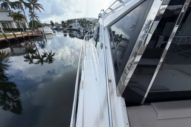 Slide: The Image of 2018 Regal 53 Sport Coupe yacht docked by a serene waterfront with palm trees. - 37