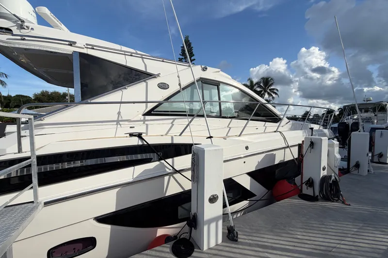 Slide: The Image of 2018 Regal 53 Sport Coupe yacht docked under a partly cloudy sky. - 15