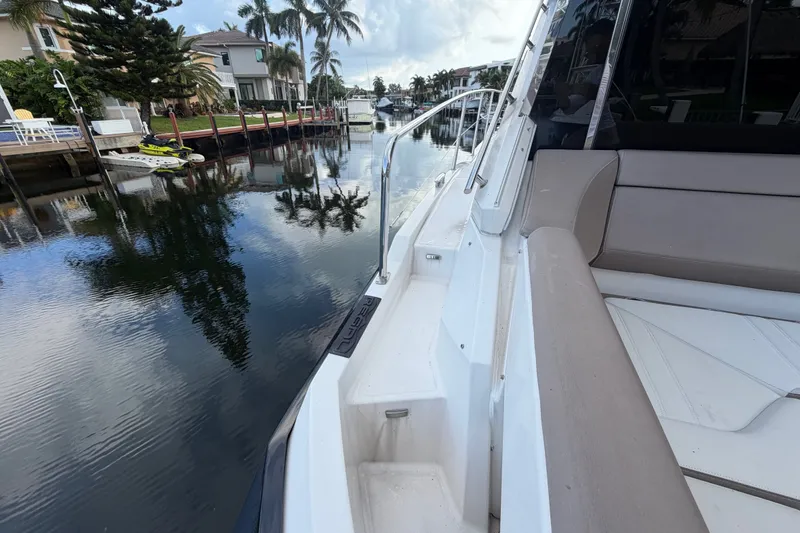 Slide: The Image of 2018 Regal 53 Sport Coupe yacht docked by a serene waterfront with palm trees. - 34