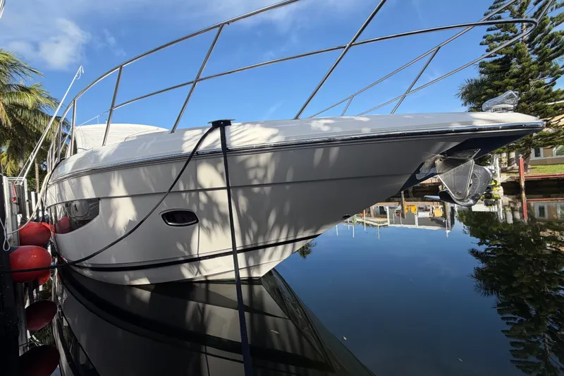 Slide: The Image of 2018 Regal 53 Sport Coupe yacht docked on calm water, surrounded by trees. - 20