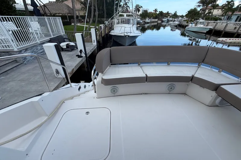 Slide: The Image of 2018 Regal 53 Sport Coupe yacht with spacious deck seating by a serene marina. - 29