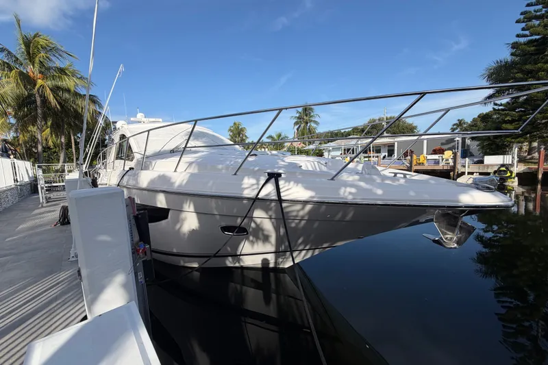 Slide: The Image of 2018 Regal 53 Sport Coupe yacht docked by palm trees under clear blue sky. - 18