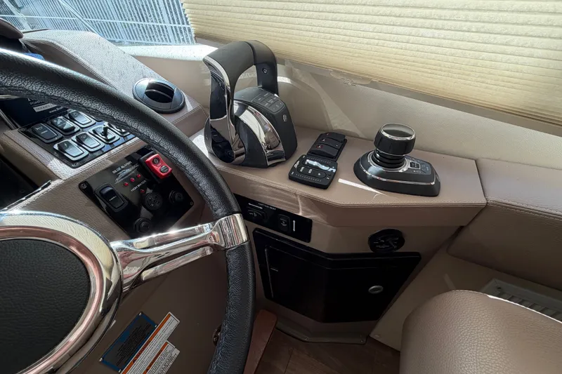 Slide: The Image of Cockpit controls of a 2018 Regal 53 Sport Coupe yacht, featuring steering wheel and throttle. - 77