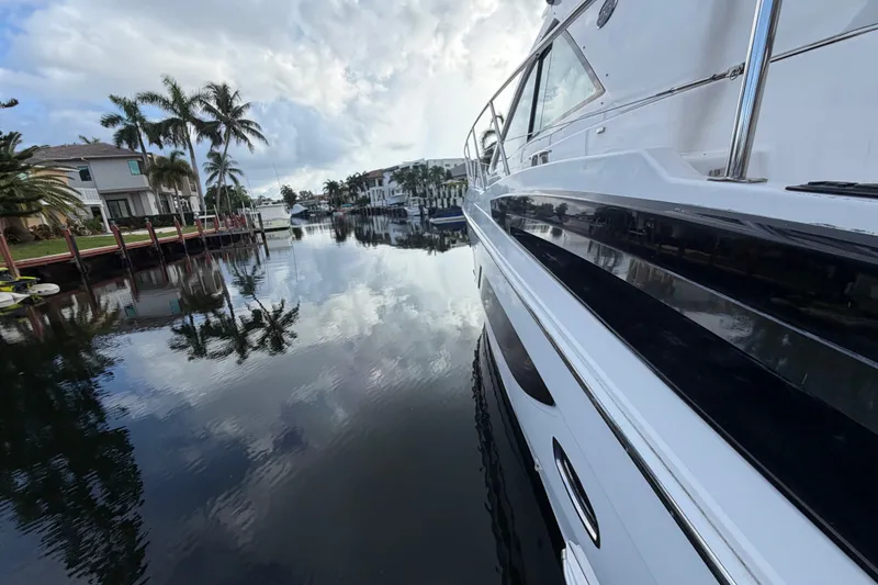 Slide: The Image of 2018 Regal 53 Sport Coupe yacht docked by palm-lined waterfront homes. - 36