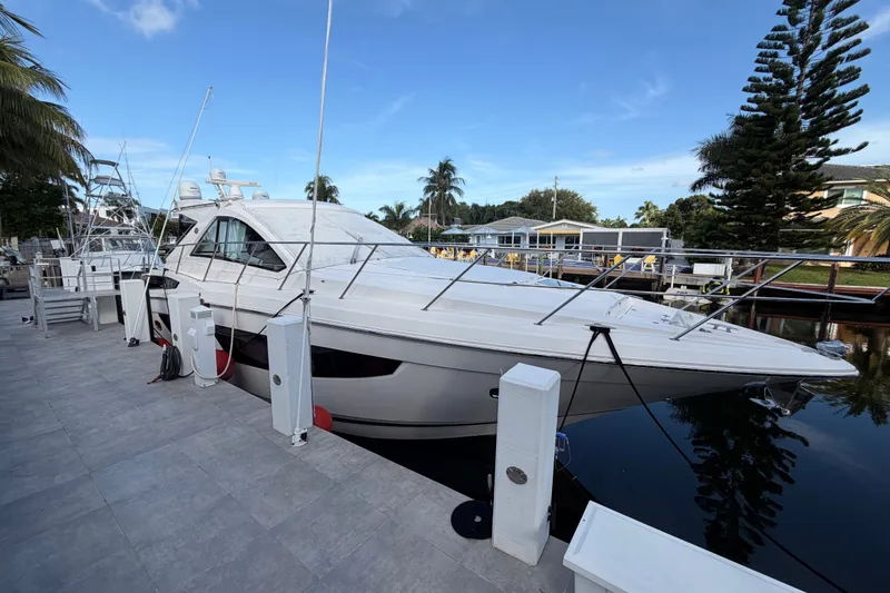 Slide: The Image of 2018 Regal 53 Sport Coupe yacht docked by palm trees and waterfront homes. - 9