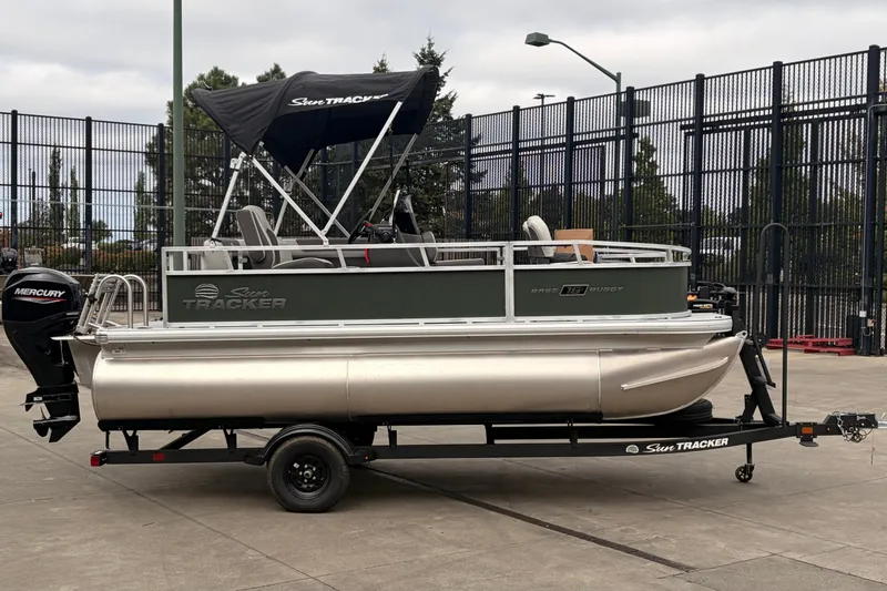The Image of 2027 Sun Tracker Bass Buggy 16 XL Select pontoon boat on trailer, outdoor setting. - 0