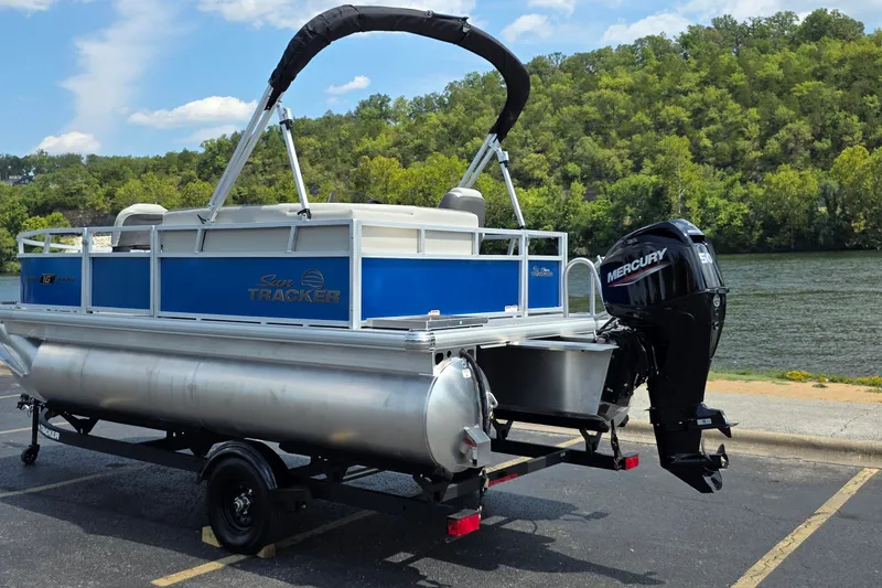 The Image of 2027 Sun Tracker Bass Buggy 16 XL Select pontoon boat with Mercury engine by a river. - 1