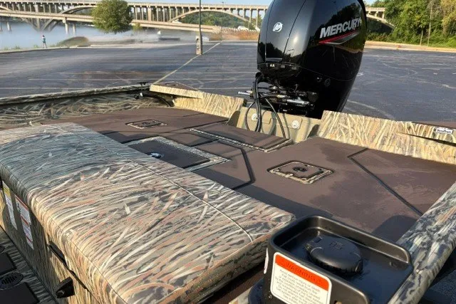 Slide: The Image of 2027 Tracker Grizzly 2072 CC boat with camo design and Mercury engine by a river. - 18