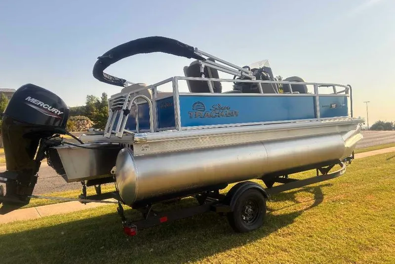 Slide: The Image of 2027 Sun Tracker Bass Buggy 16 XL Select pontoon boat on trailer, parked on grass. - 14