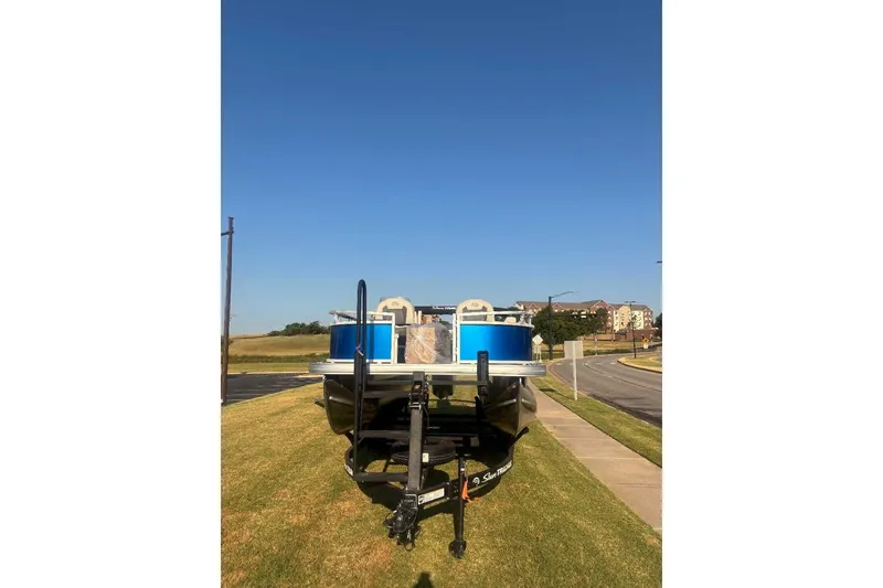 Slide: The Image of 2027 Sun Tracker Bass Buggy 16 XL Select pontoon boat on trailer, parked on grass. - 15