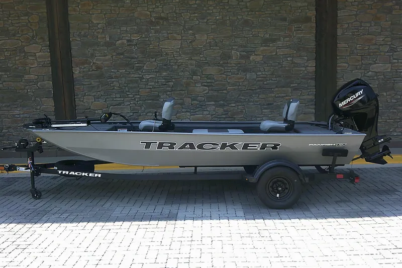 The Image of 2027 Tracker Panfish 17 boat with Mercury engine on trailer, parked by stone wall. - 0