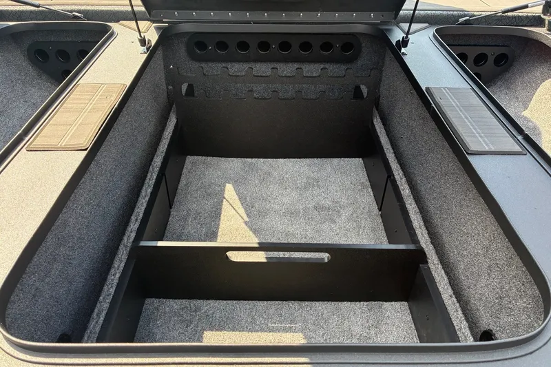Slide: The Image of Interior storage compartment of 2027 Tracker Savage 215 boat, featuring carpeted surfaces and organized layout. - 13
