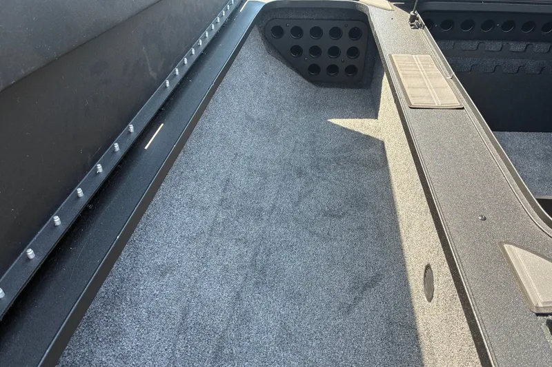 Slide: The Image of Interior view of 2027 Tracker Savage 215 boat with carpeted flooring and storage compartments. - 14