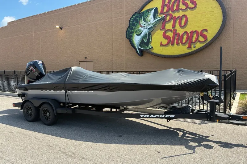 Slide: The Image of 2027 Tracker Savage 215 boat covered on trailer outside Bass Pro Shops. - 17