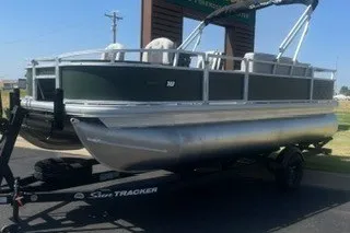 The Image of 2027 Sun Tracker Bass Buggy 18 DLX pontoon boat on trailer, parked outdoors. - 0