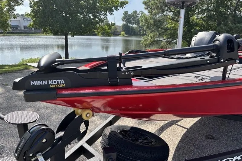 Slide: The Image of Red 2027 Tracker Savage 215 boat with Minn Kota Maxxum motor by a lake. - 13