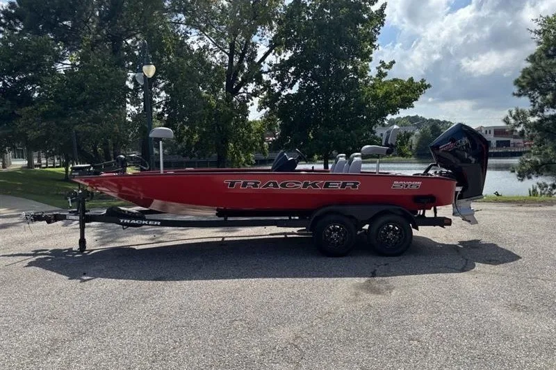 The Image of 2027 Tracker Savage 215 boat on trailer, parked near a lake under cloudy sky. - 0