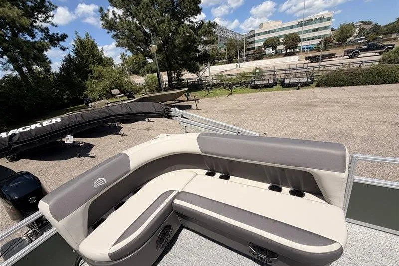 Slide: The Image of 2027 Sun Tracker Bass Buggy 16 XL Select pontoon boat with cushioned seating, parked outdoors. - 20