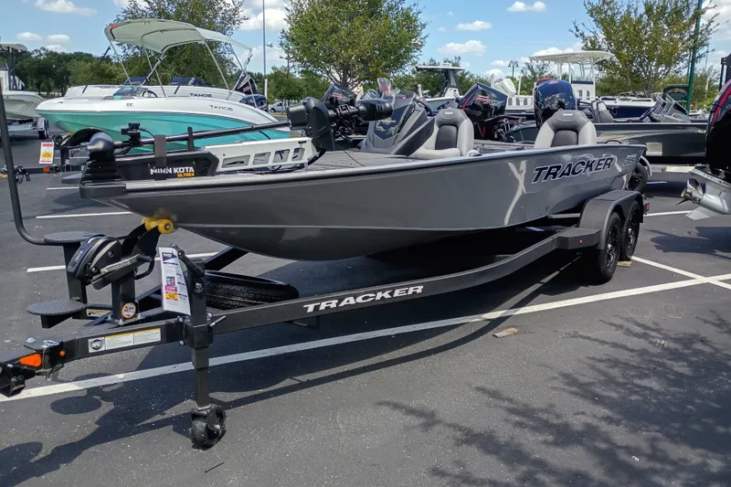 The Image of 2027 Tracker Savage 215 boat on trailer in parking lot, surrounded by other boats. - 0