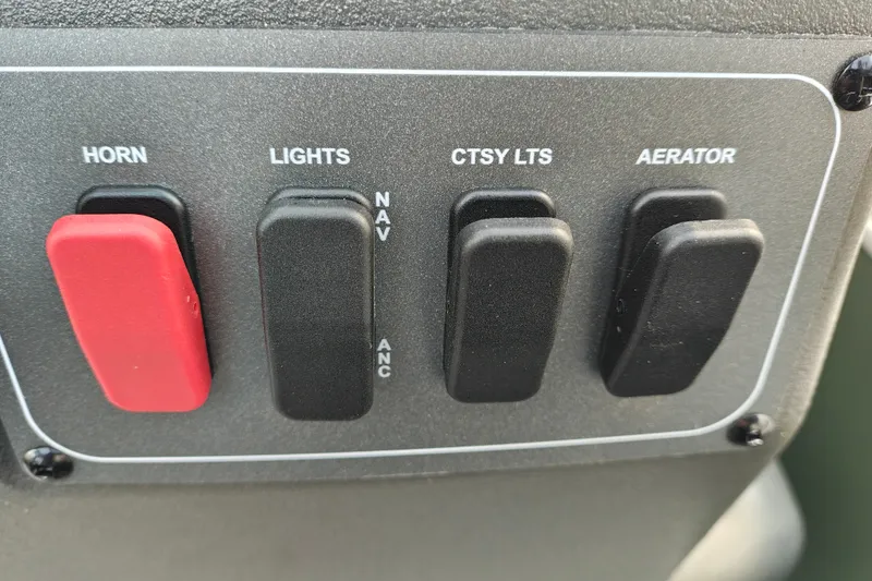 Slide: The Image of Control panel of 2027 Sun Tracker Bass Buggy 18 DLX with switches for horn, lights, and aerator. - 24