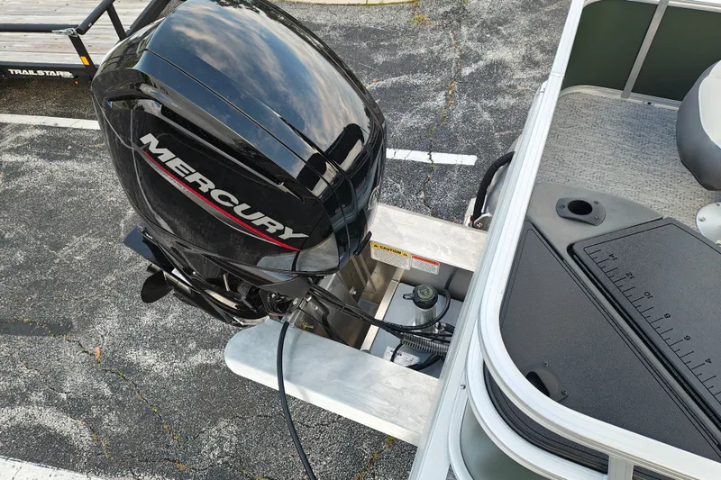 Slide: The Image of 2027 Sun Tracker Bass Buggy 18 DLX with Mercury outboard motor, docked on pavement. - 19