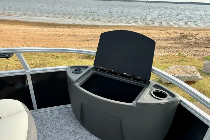 Slide: The Image of Open storage compartment on 2027 Sun Tracker Bass Buggy 18 DLX pontoon boat by the shore. - 14