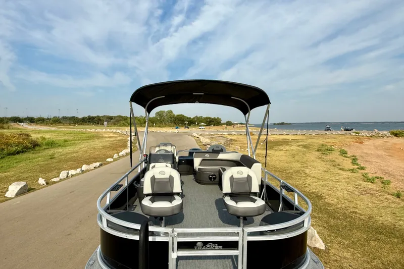 Slide: The Image of 2027 Sun Tracker Bass Buggy 18 DLX pontoon boat near scenic lakeside. - 21