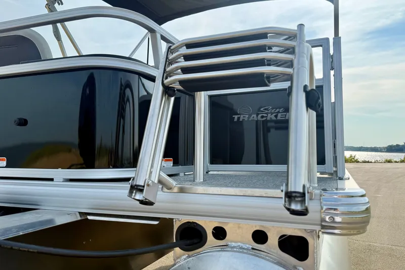 Slide: The Image of 2027 Sun Tracker Bass Buggy 18 DLX pontoon boat with sleek black exterior and sturdy ladder. - 19