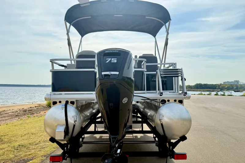 Slide: The Image of 2027 Sun Tracker Bass Buggy 18 DLX pontoon boat with Mercury 75 engine by a lake. - 18