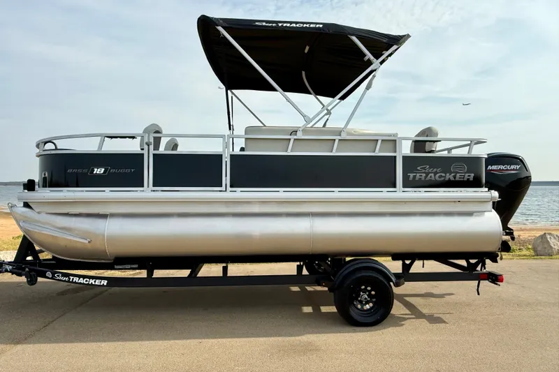 Slide: The Image of 2027 Sun Tracker Bass Buggy 18 DLX pontoon boat on trailer by the water. - 22