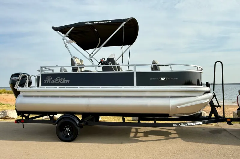 Slide: The Image of 2027 Sun Tracker Bass Buggy 18 DLX pontoon boat on trailer by the water. - 17