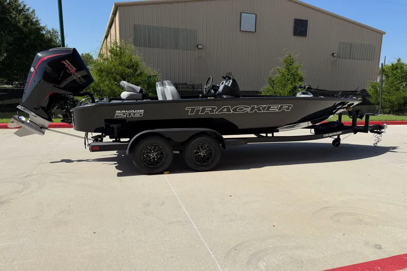 Slide: The Image of 2027 Tracker Savage 215 boat on trailer, parked outdoors near a building. - 26