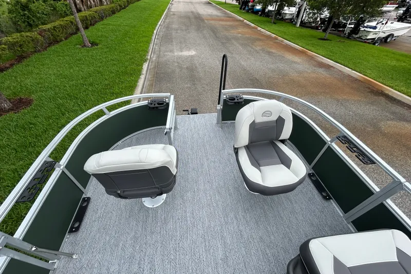 Slide: The Image of 2027 Sun Tracker Bass Buggy 16 XL Select pontoon boat with comfortable seating on a paved road. - 13