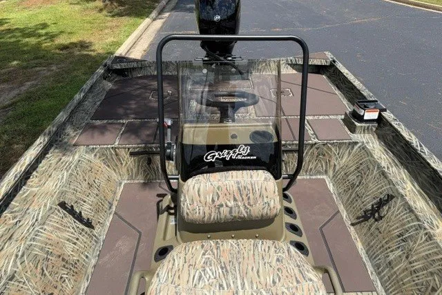 Slide: The Image of 2027 Tracker Grizzly 2072 CC boat with camouflage seating and console, parked on pavement. - 13