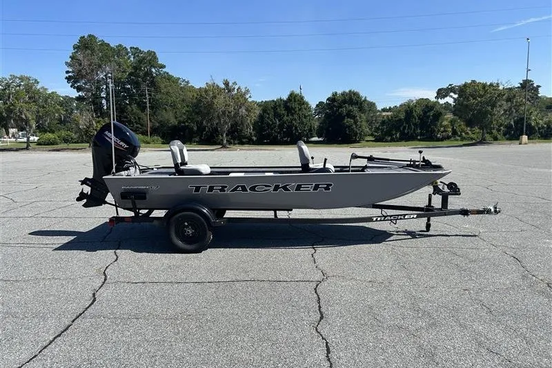 The Image of 2027 Tracker Panfish 17 boat on trailer in parking lot, clear sky background. - 0