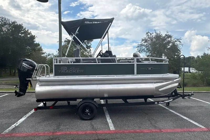 The Image of 2027 Sun Tracker Bass Buggy 16 XL Select pontoon boat on trailer in parking lot. - 0