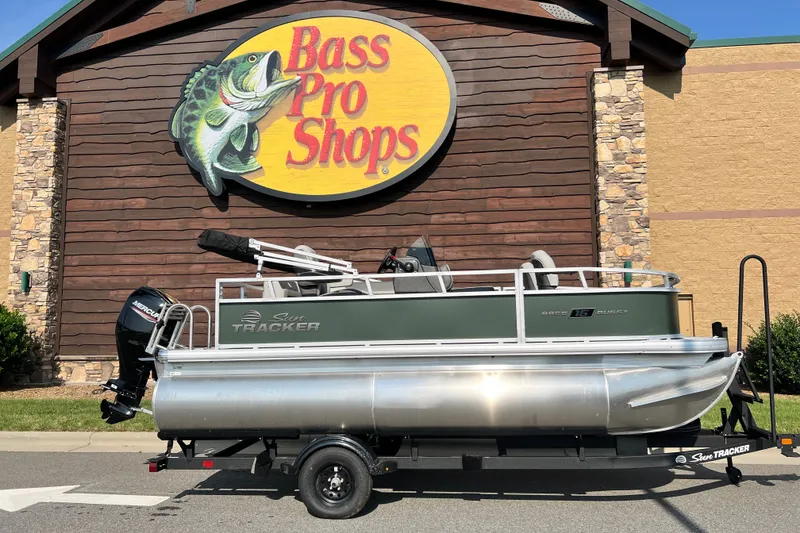 The Image of Sun Tracker Bass Buggy 16 XL Select 2027 pontoon boat at Bass Pro Shops entrance. - 0