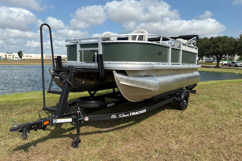 Slide: The Image of 2027 Sun Tracker Bass Buggy 16 XL Select pontoon boat on trailer by a lake. - 59