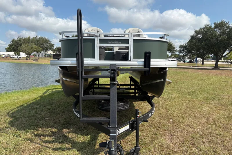 Slide: The Image of 2027 Sun Tracker Bass Buggy 16 XL Select pontoon boat on trailer by a lake. - 58
