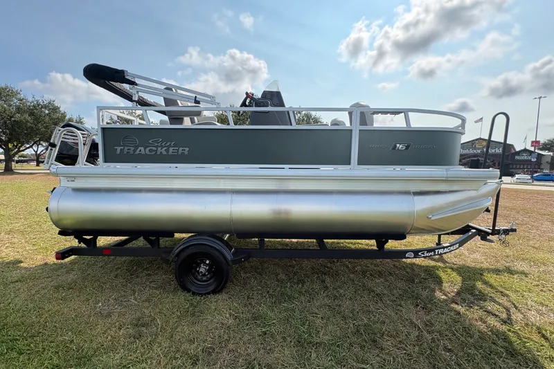 Slide: The Image of 2027 Sun Tracker Bass Buggy 16 XL Select pontoon boat on grassy area under cloudy sky. - 63
