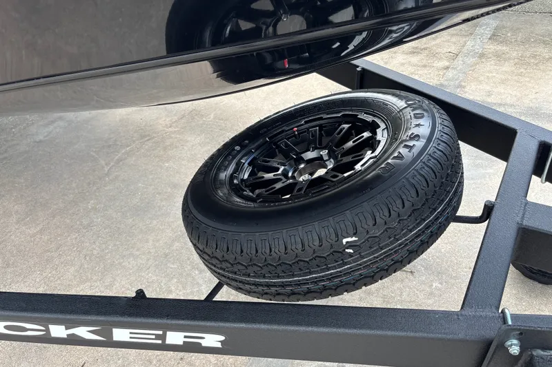 Slide: The Image of 2027 Tracker Savage 215 trailer with spare tire on concrete surface. - 22