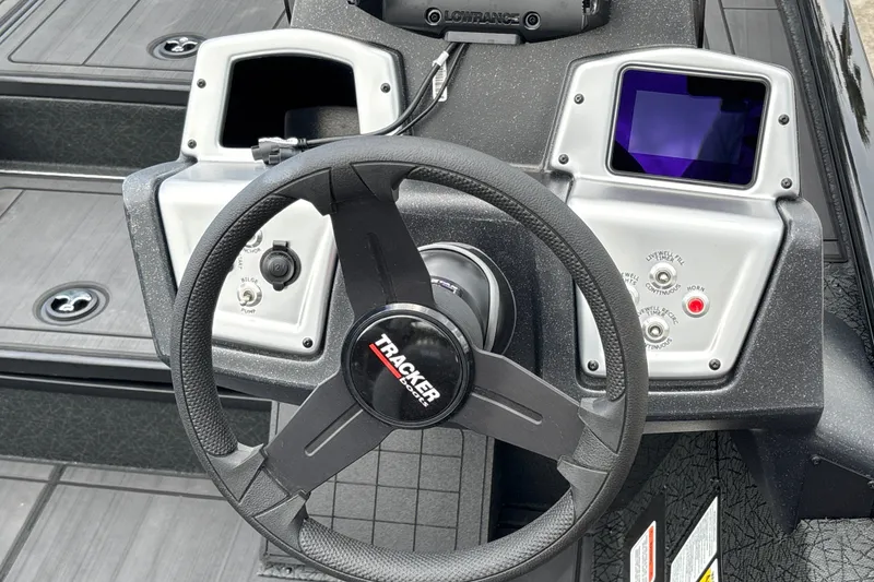 Slide: The Image of Steering wheel and dashboard of 2027 Tracker Savage 215 boat, featuring control panels and display. - 18