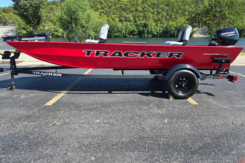 The Image of Red 2027 Tracker Panfish 17 boat on trailer, parked near a scenic lake. - 0