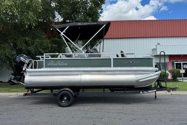 The Image of 2027 Sun Tracker Bass Buggy 18 DLX pontoon boat on trailer, parked outdoors. - 0