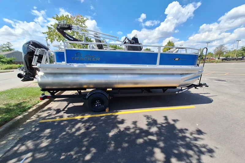 The Image of 2027 Sun Tracker Bass Buggy 18 DLX pontoon boat parked in a sunny lot. - 0