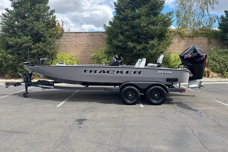 The Image of 2027 Tracker Savage 215 boat on trailer, parked outdoors with trees in background. - 0