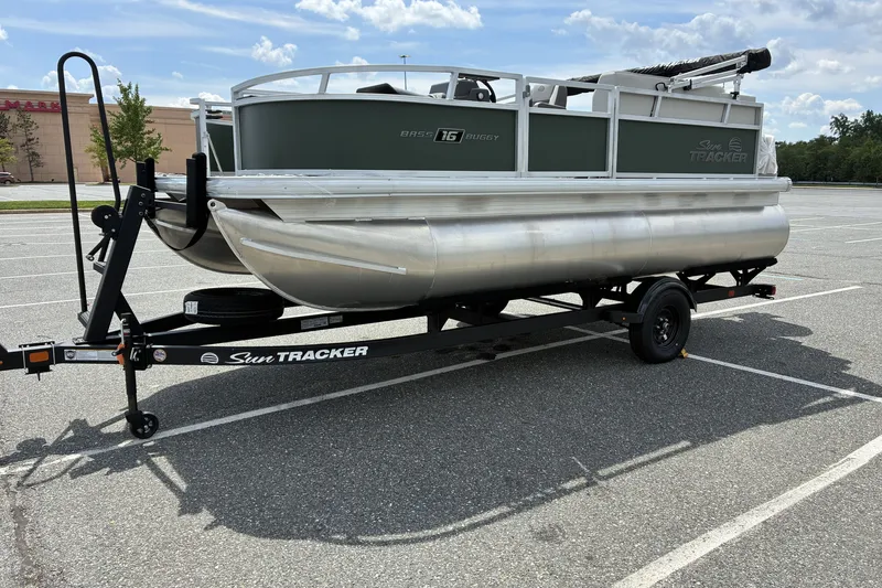 The Image of 2027 Sun Tracker Bass Buggy 16 XL Select pontoon boat on trailer in parking lot. - 0